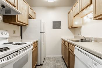 A kitchen with white appliances and wooden cabinets and a white refrigerator